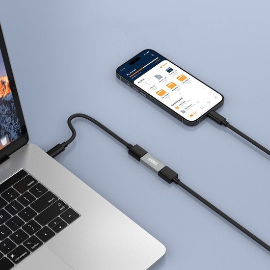 Een zwarte verbindingskabel tussen een laptop en een smartphone op een lichtblauwe ondergrond