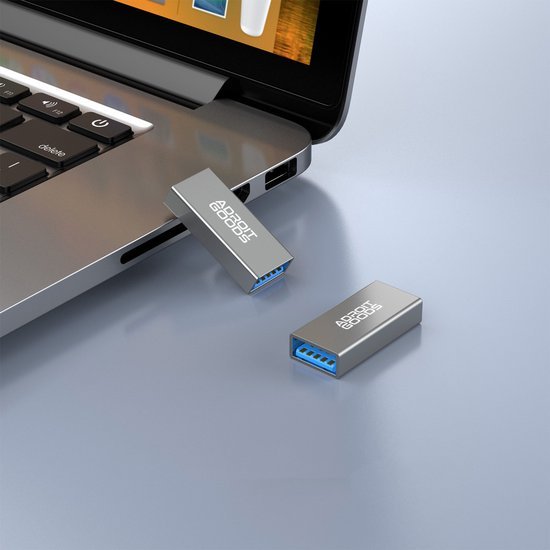 Twee metalen USB-sticks waarbij één in een laptop is aangesloten op een lichtgrijze ondergrond