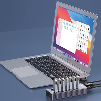 Laptop met open scherm en aangesloten hub met zes USB-sticks in een minimalistische setting