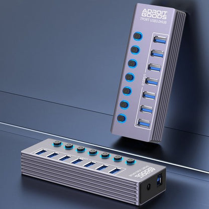 grijs metalen USB-hub met zeven poorten en individuele aan/uit-knoppen op blauwe achtergrond