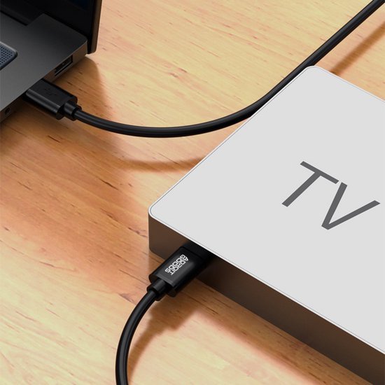 Zwarte kabels verbonden tussen een laptop en een apparaat met tekst TV op houten oppervlak