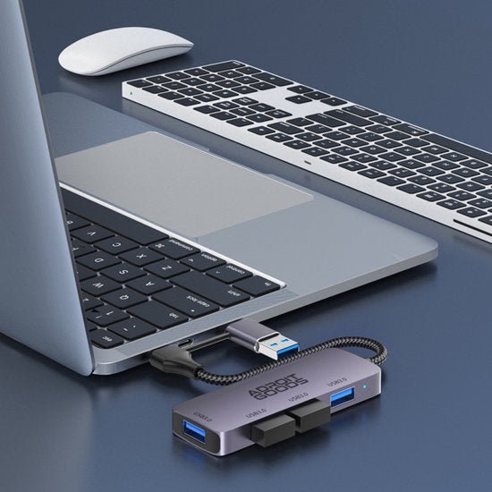 Laptop met aangesloten USB-hub en draadloze toetsenbord en muis op een blauwe ondergrond