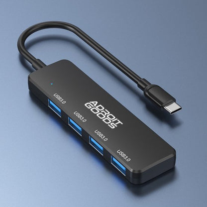zwarte USB-C hub met vier USB 3.0 poorten en korte kabel op blauwe achtergrond