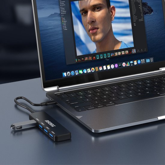 Zwarte USB-hub aangesloten op een laptop met meerdere poorten en USB-sticks erbij