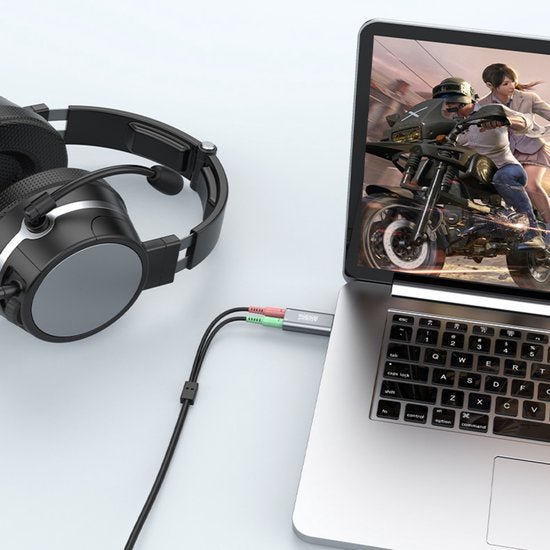 Hoofdtelefoon met microfoon aangesloten op laptop die een actiespel met motor toont