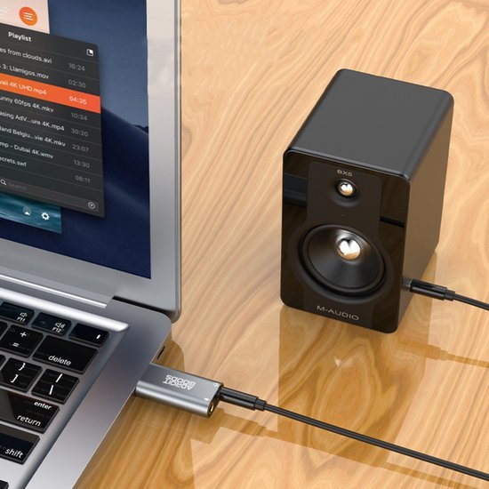 Laptop met aangesloten zwarte M-Audio speaker op houten tafelblad