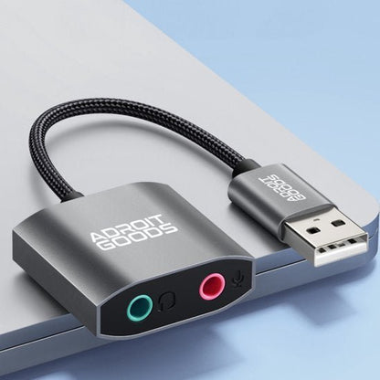 Zilverkleurige AdroitGoods audio adapter met USB aansluiting en twee 3,5 mm poorten voor microfoon en koptelefoon.