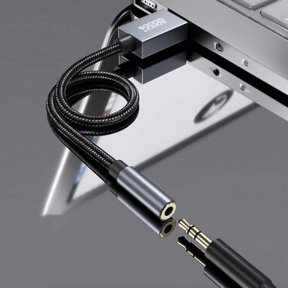 zwart gevlochten audiokabel met metalen connectoren aangesloten op een laptoppoort