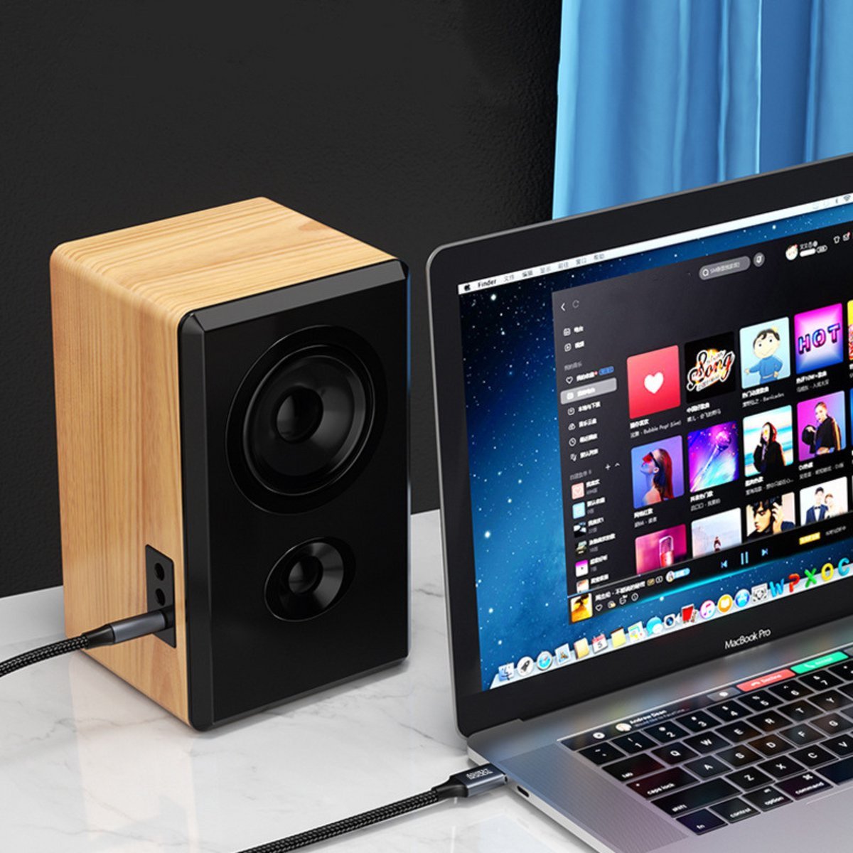 Houten luidspreker met zwarte voorkant naast een laptop met muziekapp op een bureau