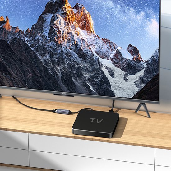 Een moderne televisie met berglandschap op scherm en een zwart tv-box apparaat op houten meubel.