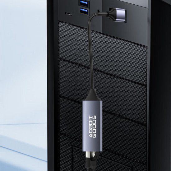 USB-verlengkabel met metalen behuizing en AdroitGoods logo aangesloten op pc achterkant