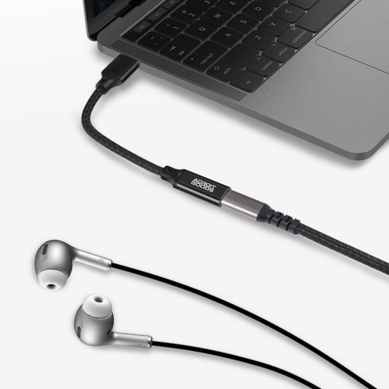Zwarte AdroitGoods audiokabel aangesloten op laptop met zilveren oordopjes ernaast