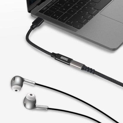 Zwarte AdroitGoods audiokabel aangesloten op laptop met zilveren oordopjes ernaast