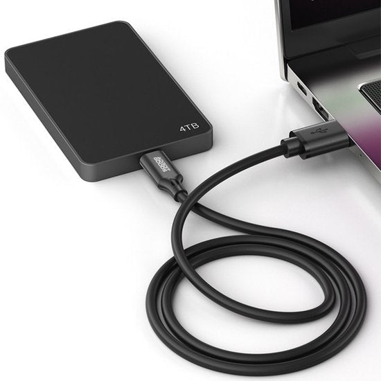 Zwarte externe harde schijf met 4TB capaciteit verbonden met laptop via USB-kabel