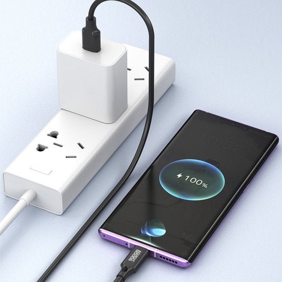Smartphone die via een zwarte kabel volledig wordt opgeladen met een wit stopcontactblok
