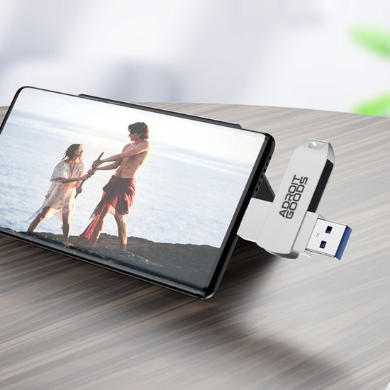 Smartphone met uitklapbare standaard en usb-stick op houten tafelblad in natuurlijke omgeving