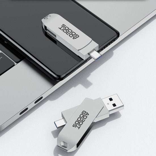 twee witte USB-sticks met AdroitGoods-logo, één aangesloten op telefoon en één op laptop