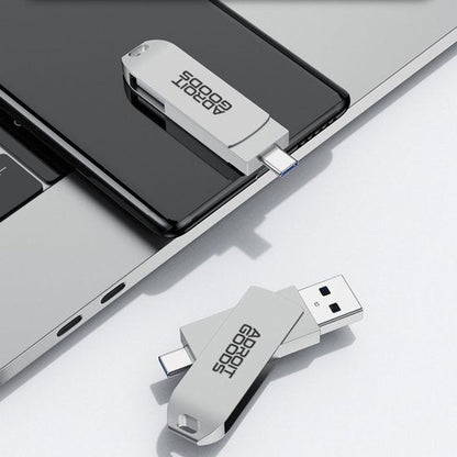twee witte USB-sticks met AdroitGoods-logo, één aangesloten op telefoon en één op laptop