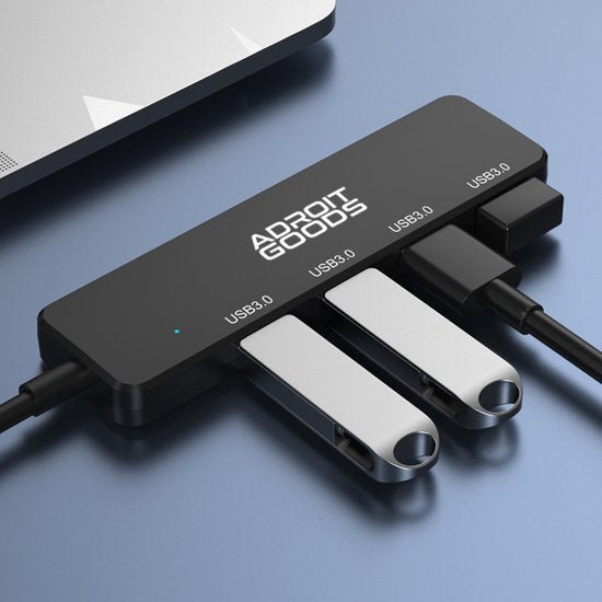 Zwarte USB 3.0 hub met vier aangesloten apparaten op een blauwe ondergrond naast een laptop