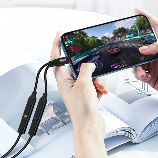 Persoon speelt racespel op smartphone met aangesloten zwarte audio- en opladerkabels.