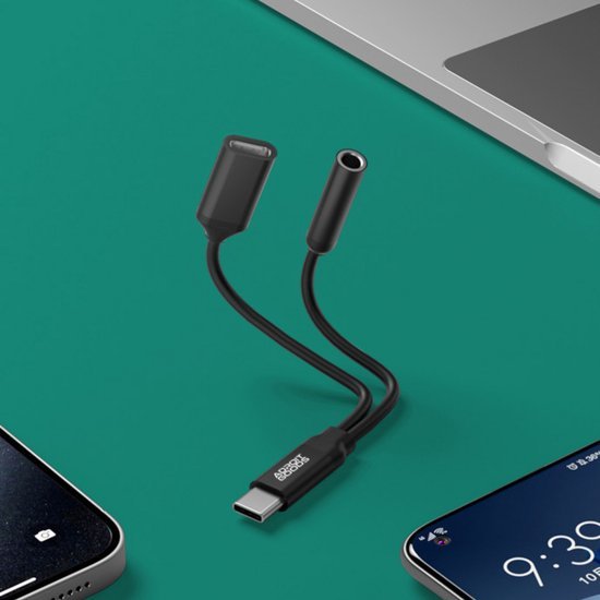 Zwarte adapterkabel met USB-C naar 3,5mm audio en oplaadpoort naast telefoons en laptop