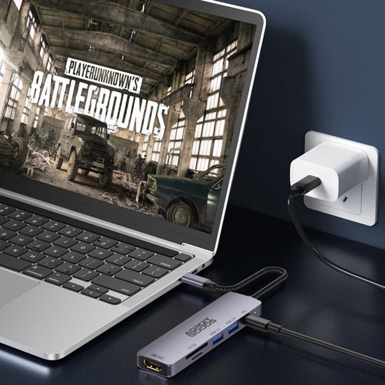 Laptop met gamingbeeldscherm, aangesloten op een compacte USB-C hub en een oplader