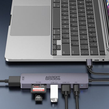 grijze AdroitGoods USB-hub aangesloten op laptop met meerdere kabels en geheugenkaarten