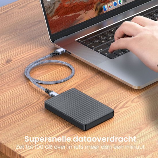 Hand die op laptoptoetsenbord werkt met externe harde schijf op houten bureau