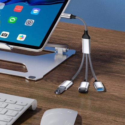 Flexibele multifunctionele USB-hub met drie aansluitingen op een houten bureau naast laptopstandaard