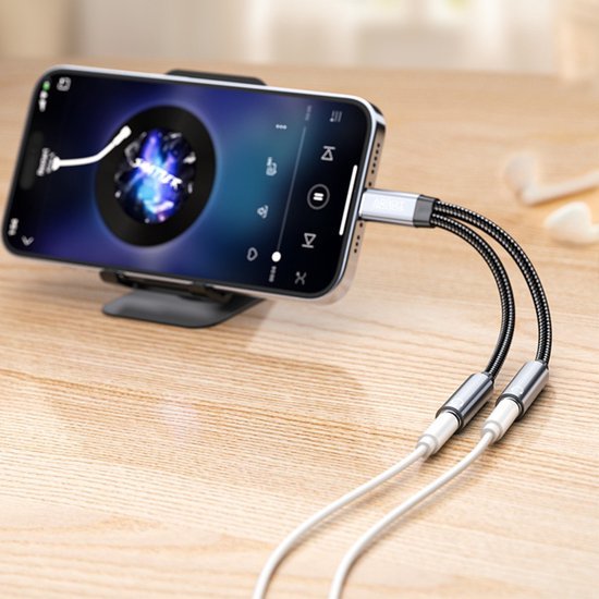 Telefoon op standaard met aangesloten audio-splitter kabels voor gelijktijdig luisteren en opladen.