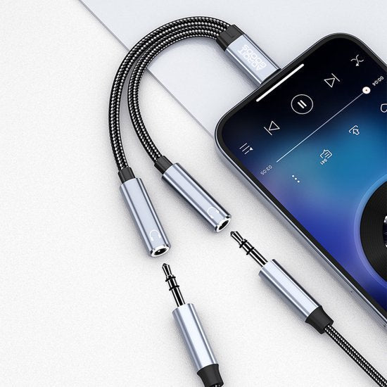 Zwarte gevlochten audio-splitterkabel met metalen aansluitingen verbonden met smartphone muziekinterface