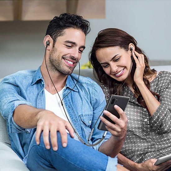 Twee lachende mensen die samen naar een smartphone luisteren met bedrade oordopjes