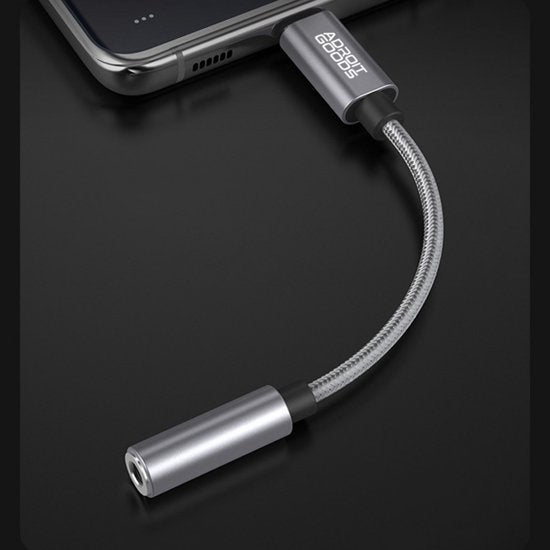 Zilverkleurige stevige audioadapter kabel aangesloten op een smartphone in een moderne setting