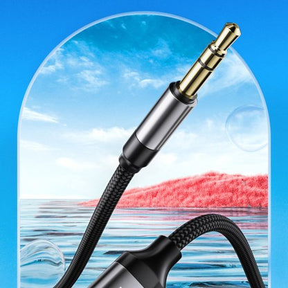 Zwarte gevlochten audiokabel met goudkleurige 3,5 mm connector tegen blauwe lucht achtergrond