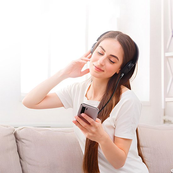 Jonge vrouw met lange haren genietend van muziek via draadloze koptelefoon en smartphone