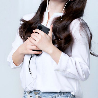 Vrouw met lang haar draagt witte blouse en houdt smartphone vast met oordopjes in haar oren