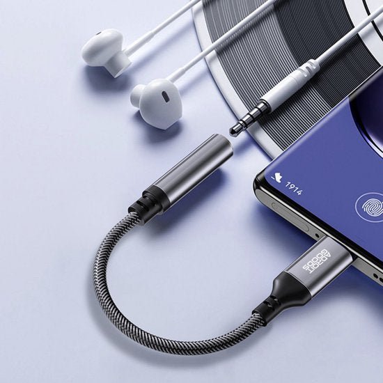 Witte oordopjes met kabeladapter aangesloten op een smartphone met ronde vinylplaat ernaast