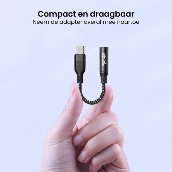 Hand houdt compacte en draagbare adapter met USB-C en audio aansluiting van AdroitGoods