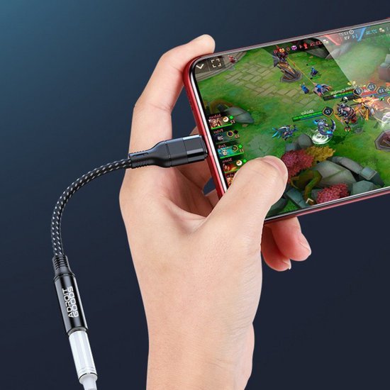 Hand houdt smartphone met AdroitGoods gevlochten kabel aangesloten tijdens het gamen.
