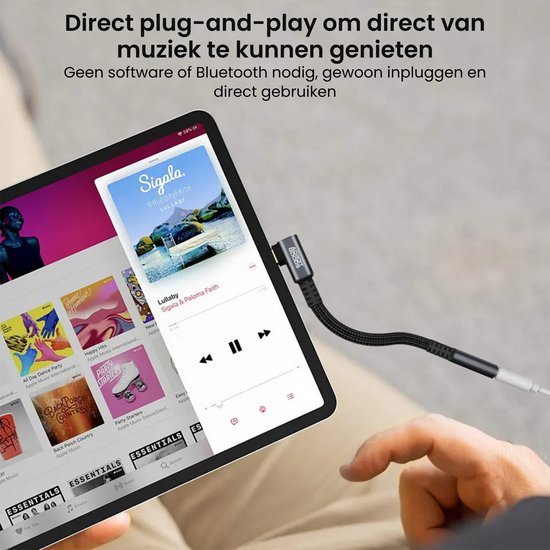Een hand sluit een adapter aan op een tablet om direct muziek te luisteren zonder bluetooth.