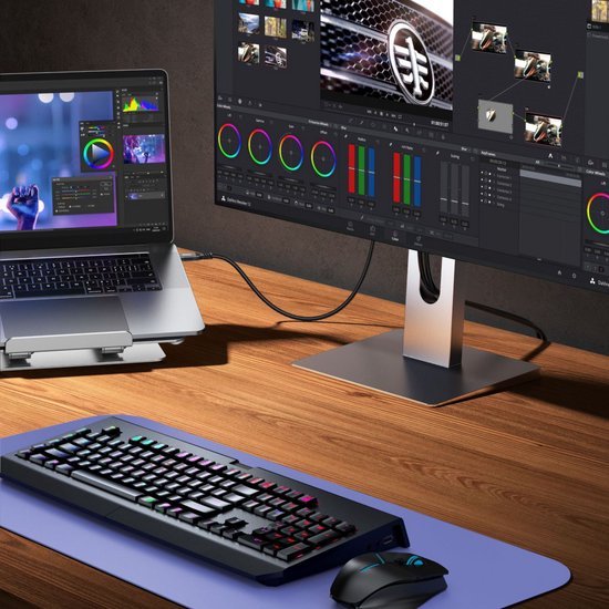 Een bureau met een laptop, extern beeldscherm met kleurcorrectiewerkruimte, toetsenbord en muis.