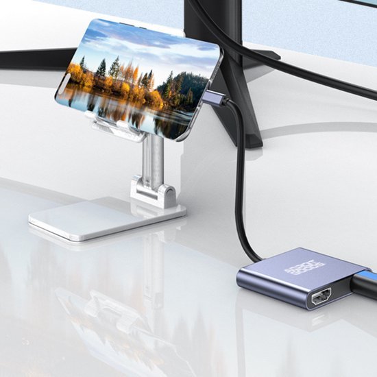 Smartphone op zilverkleurige verstelbare standaard met aangesloten kabels op wit bureau.