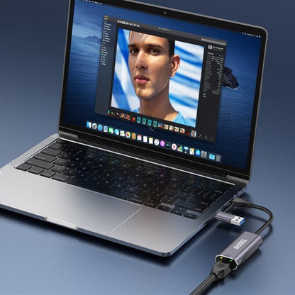 Laptop met fotobewerkingsprogramma en aangesloten adapter met meerdere poorten op bureau