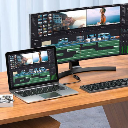 Laptop en groot beeldscherm met videobewerkingssoftware op een houten bureau in een lichte kamer