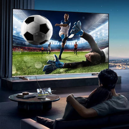 Koppel kijkt samen naar spannende voetbalwedstrijd op groot scherm in moderne woonkamer met uitzicht.