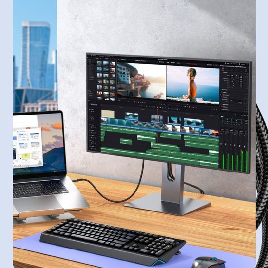 Moderne werkplek met beeldbewerking op een groot beeldscherm en laptop op bureau naast toetsenbord