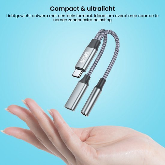 Hand houdt compacte, ultralichte adapter met twee audio-uitgangen en USB-C aansluiting vast.