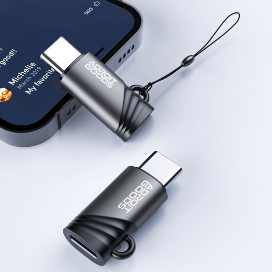 Zwarte en grijze USB-C adapters met AdroitGoods logo en koordje naast smartphone