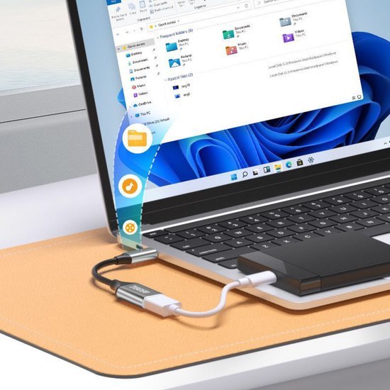 Laptop verbonden met externe opslag via USB-c adapter en kabel op bureau met muismat