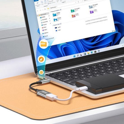 Laptop verbonden met externe opslag via USB-c adapter en kabel op bureau met muismat